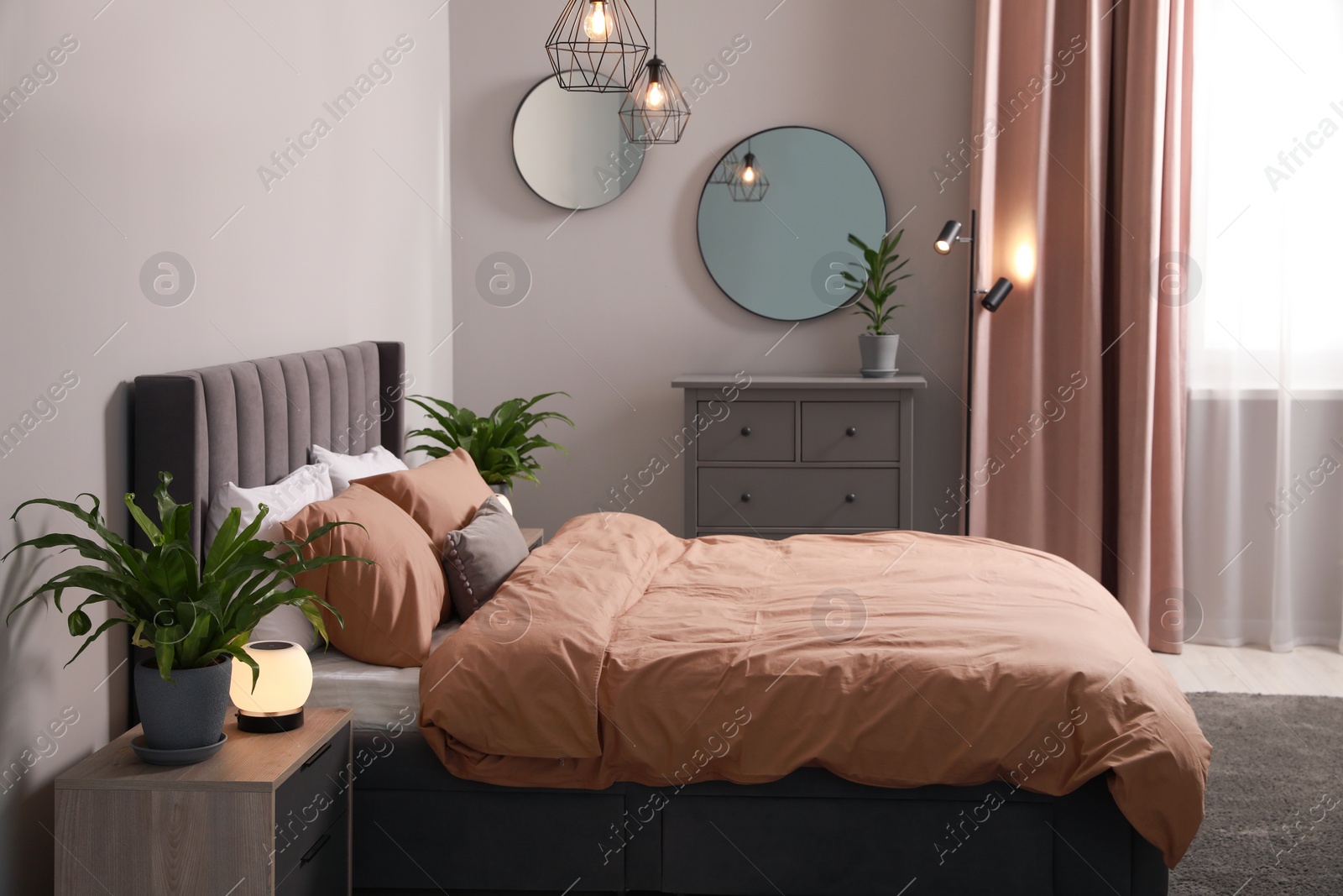 Photo of Stylish bedroom interior with comfortable bed and green houseplants