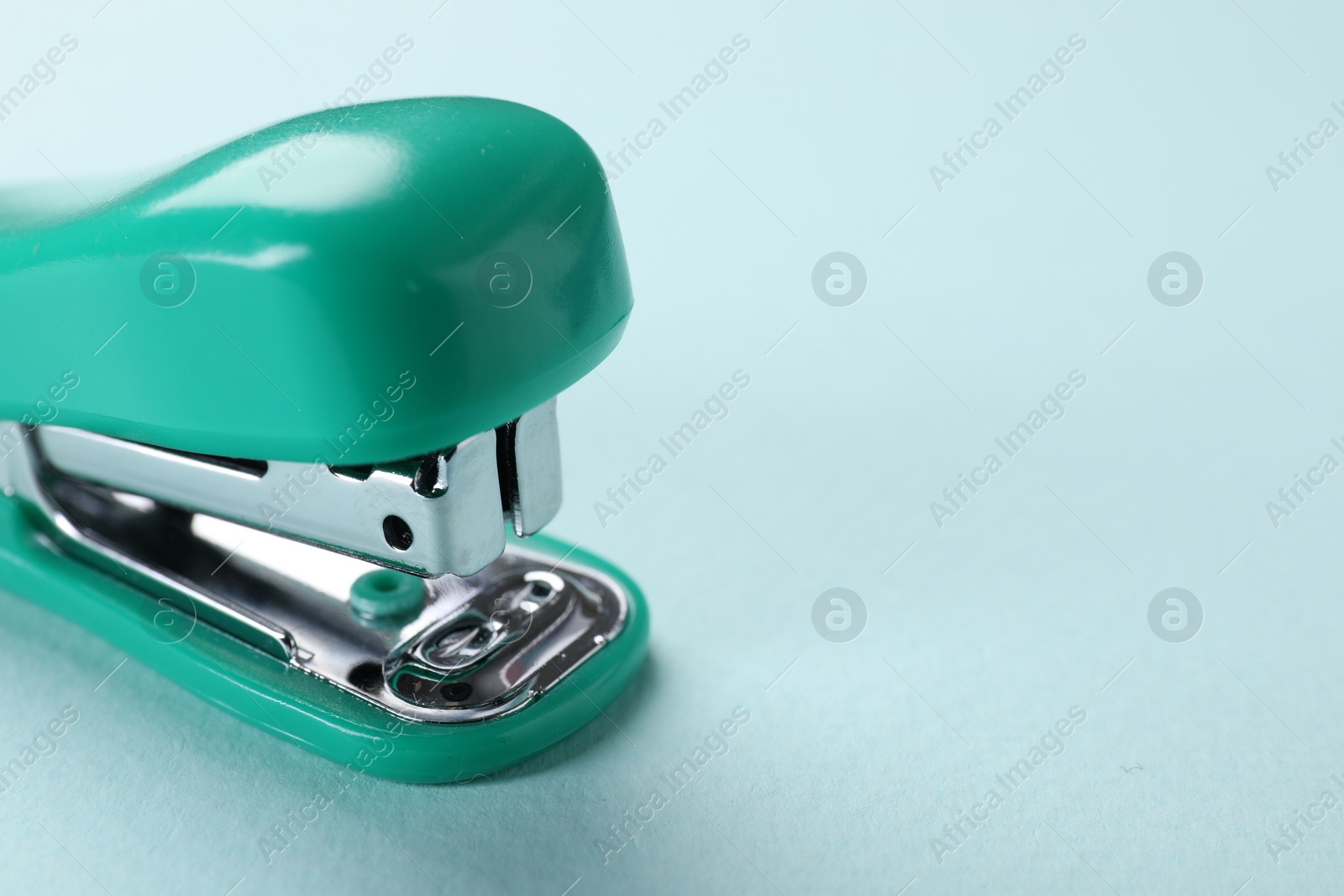 Photo of Turquoise stapler on light blue background, closeup. Space for text