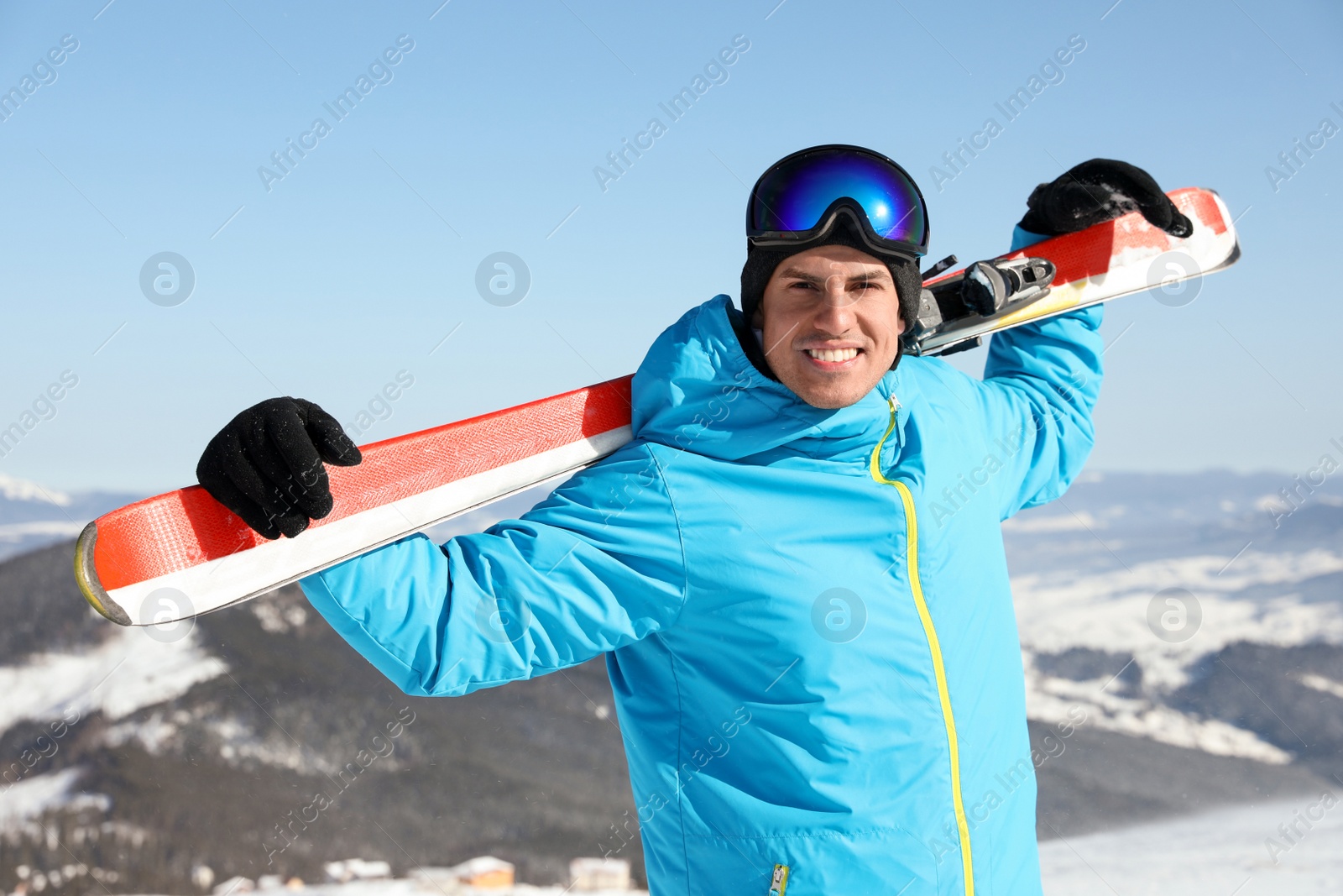 Photo of Happy man with ski equipment in mountains. Winter vacation