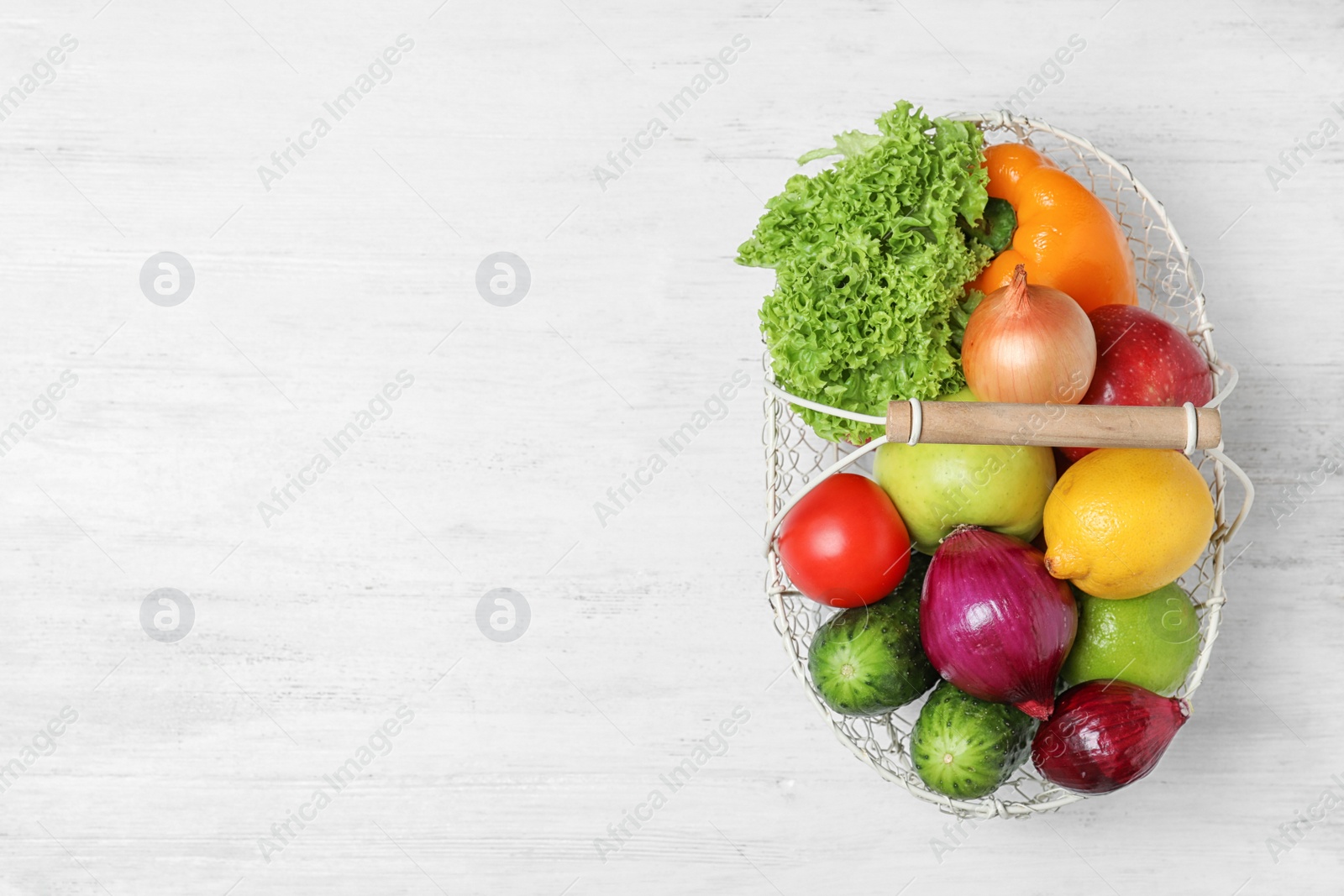 Photo of Basket with ripe fruits and vegetables on white wooden table, top view. Space for text