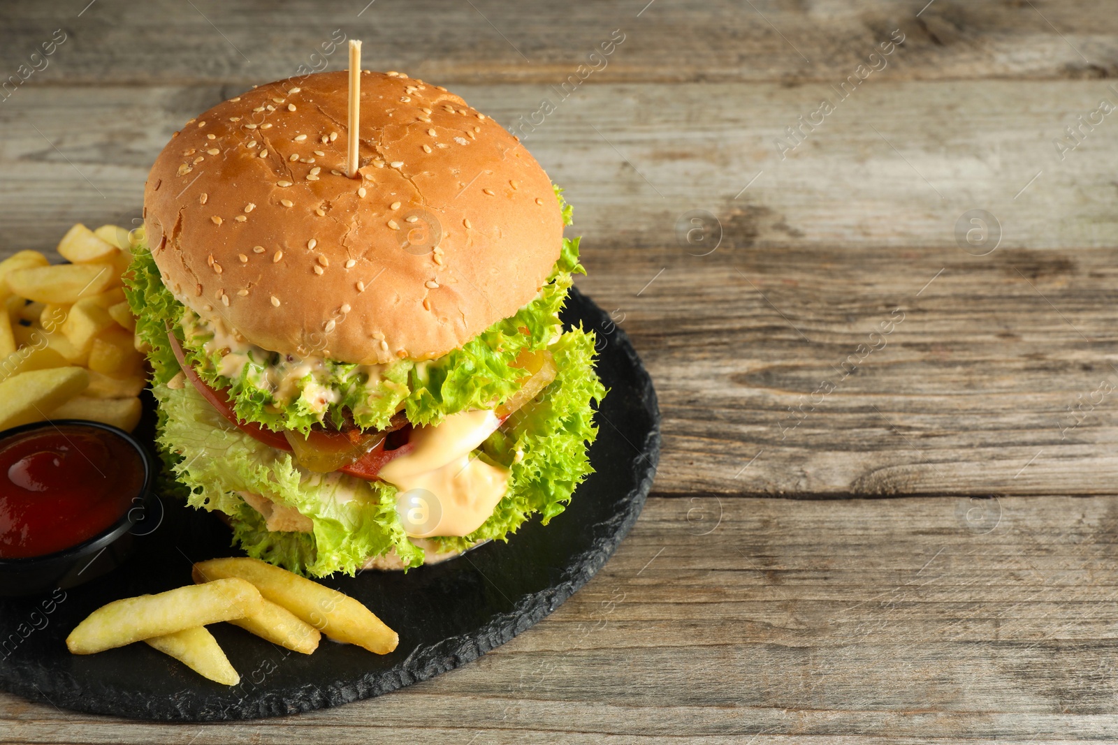 Burger with delicious patty, french fries and sauce on wooden table, space for text Photo of Burger with delicious patty, french fries and sauce on wooden table, space for text