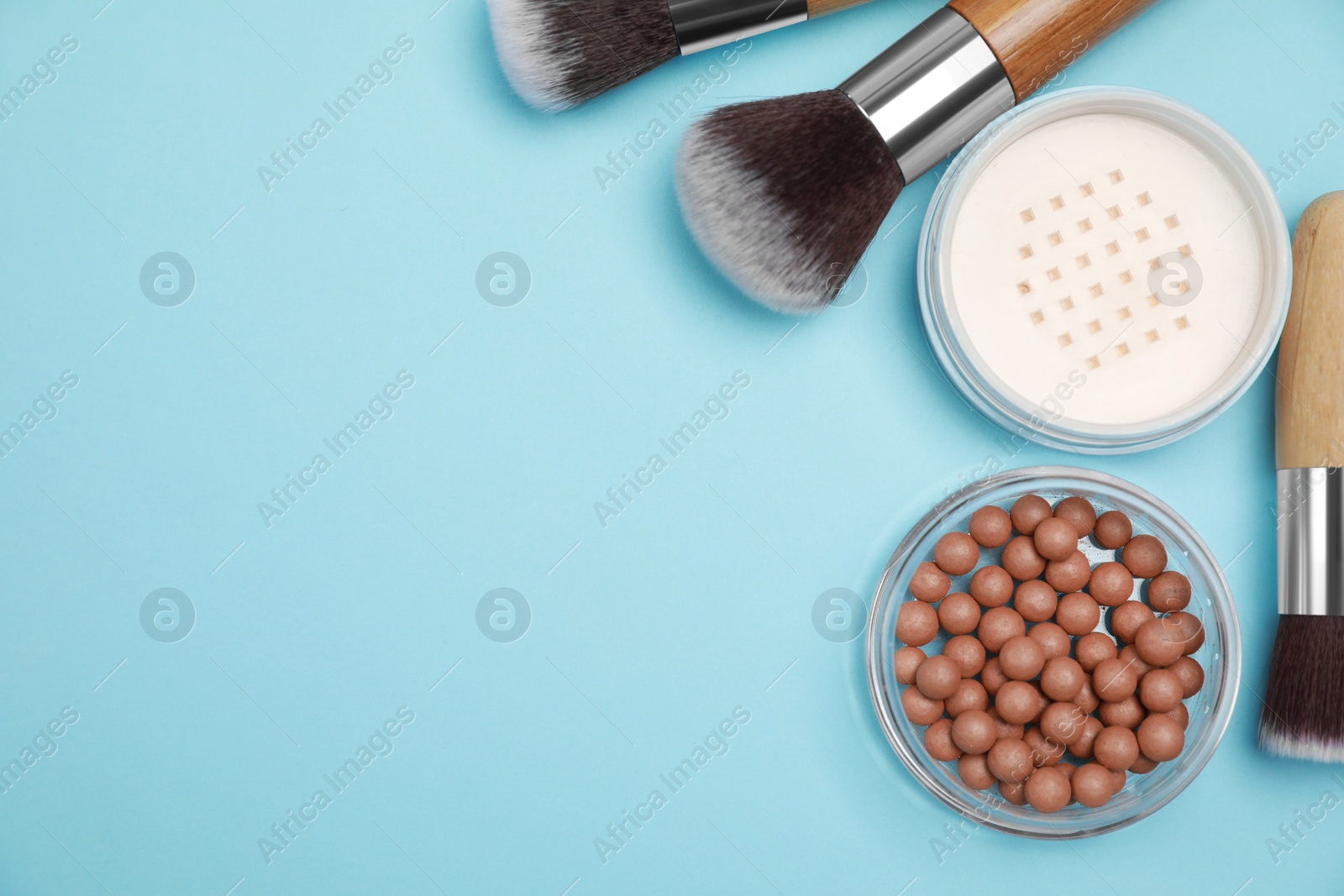 Photo of Different face powders and brushes on light blue background, flat lay. Space for text