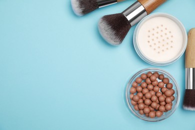 Photo of Different face powders and brushes on light blue background, flat lay. Space for text