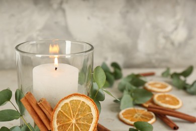 Photo of Stylish holder with burning candle and decor on light table, closeup. Space for text