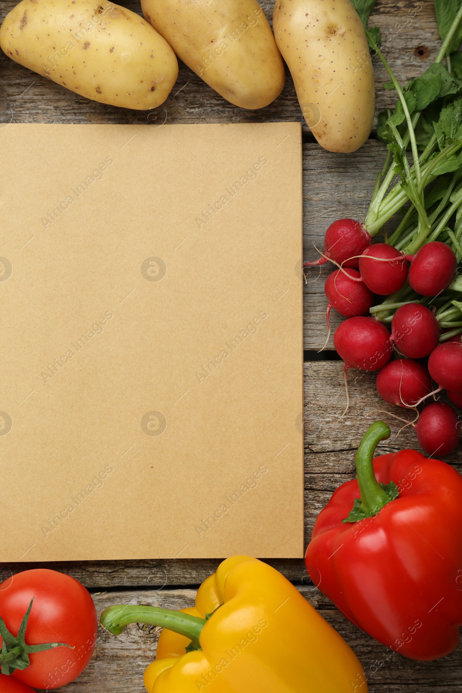 Photo of Blank recipe book and different ingredients on wooden table, flat lay. Space for text