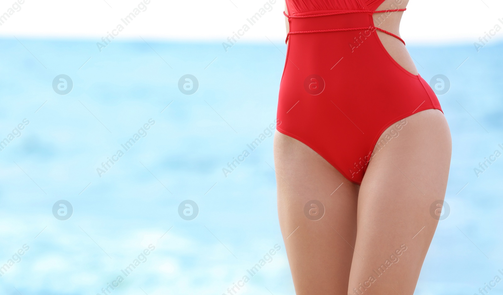 Photo of Attractive young woman in beautiful swimsuit on beach, closeup
