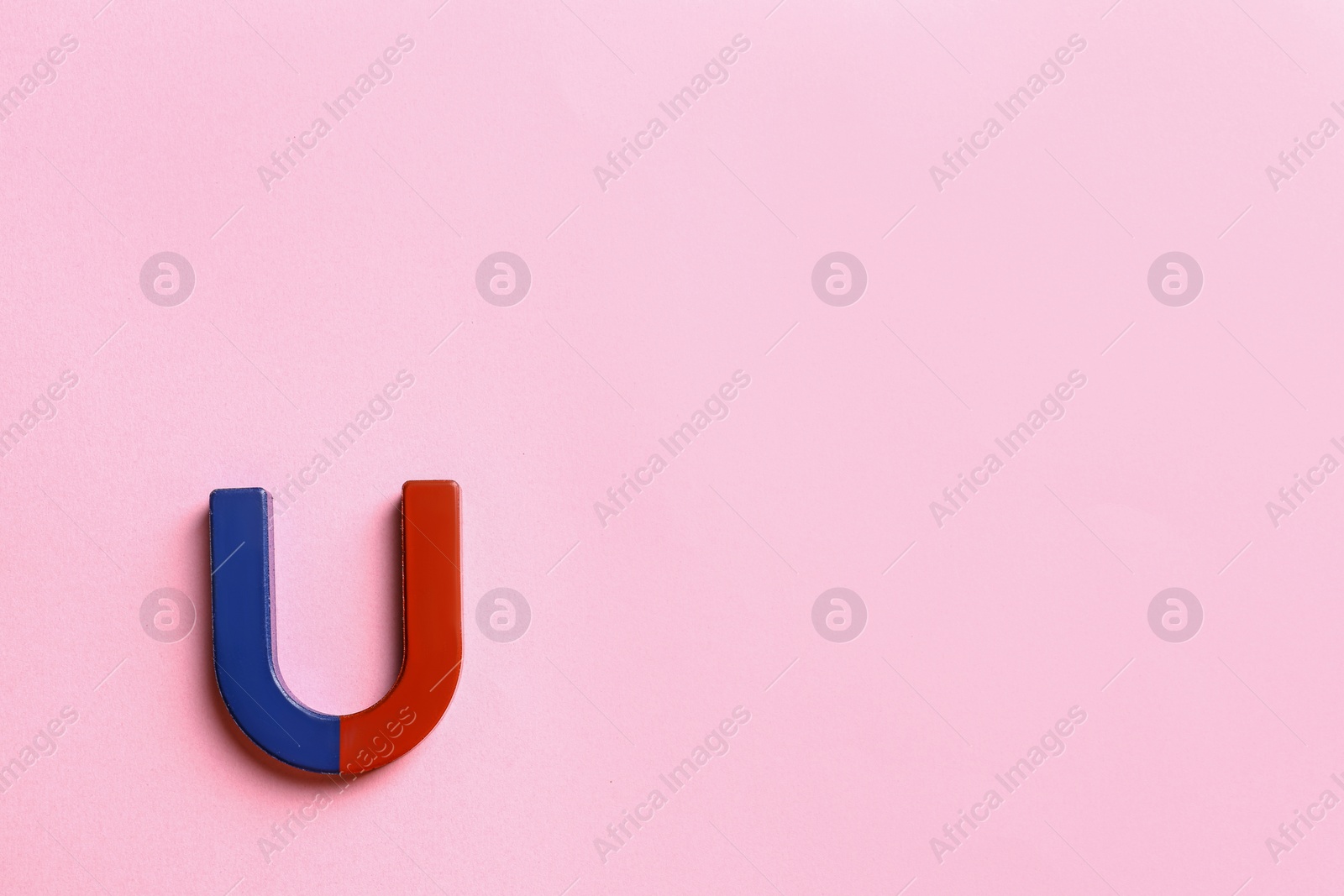 Photo of Red and blue horseshoe magnet on pink background, top view. Space for text