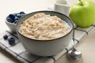 Photo of Tasty oatmeal porridge served on light wooden table