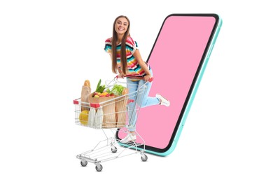 Grocery shopping via internet. Happy woman with shopping cart full of products riding out of huge smartphone on white background