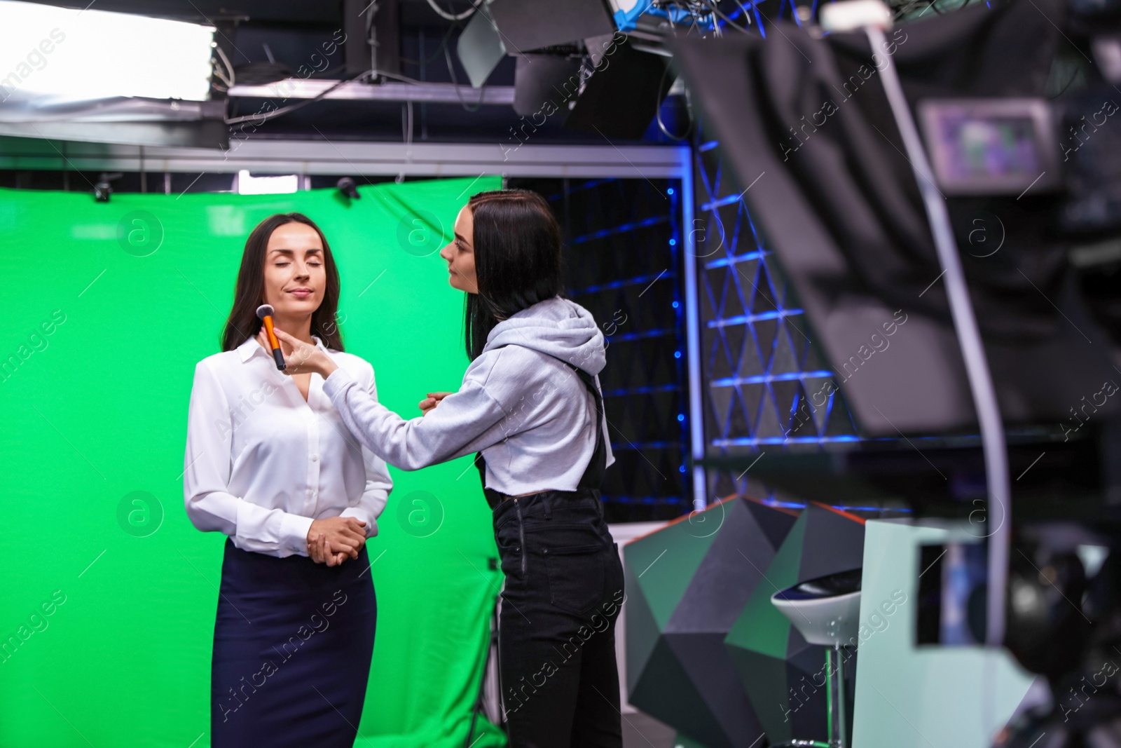 Photo of Presenter, makeup artist and video camera operator working in studio. News broadcasting