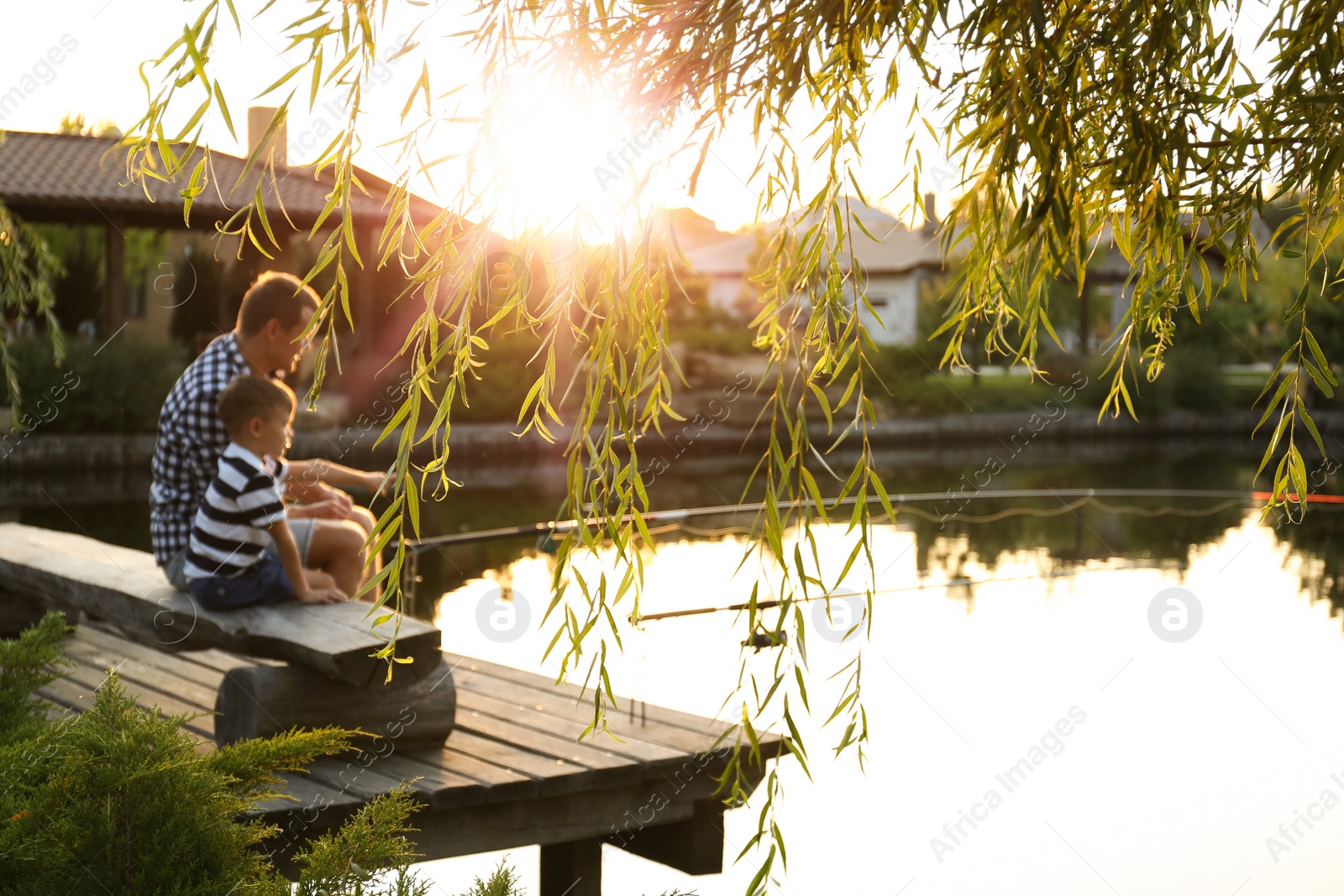 Photo of Dad and son fishing together on sunny day