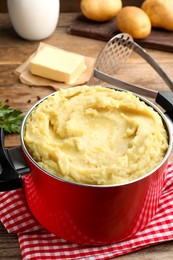 Photo of Red pot with tasty mashed potatoes on table