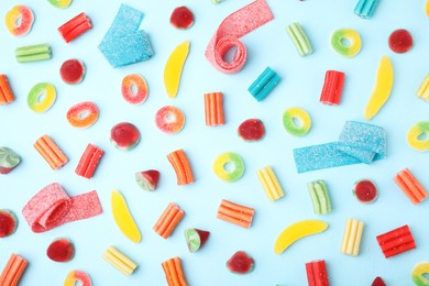 Photo of Many different jelly candies on light blue background, flat lay