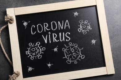 Photo of Blackboard with word Coronavirus on grey table, top view