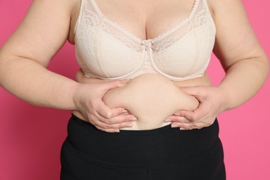 Obese woman on pink background, closeup. Weight loss surgery