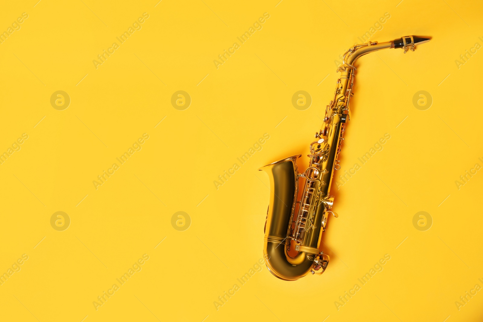 Photo of Beautiful saxophone on yellow background, top view. Space for text