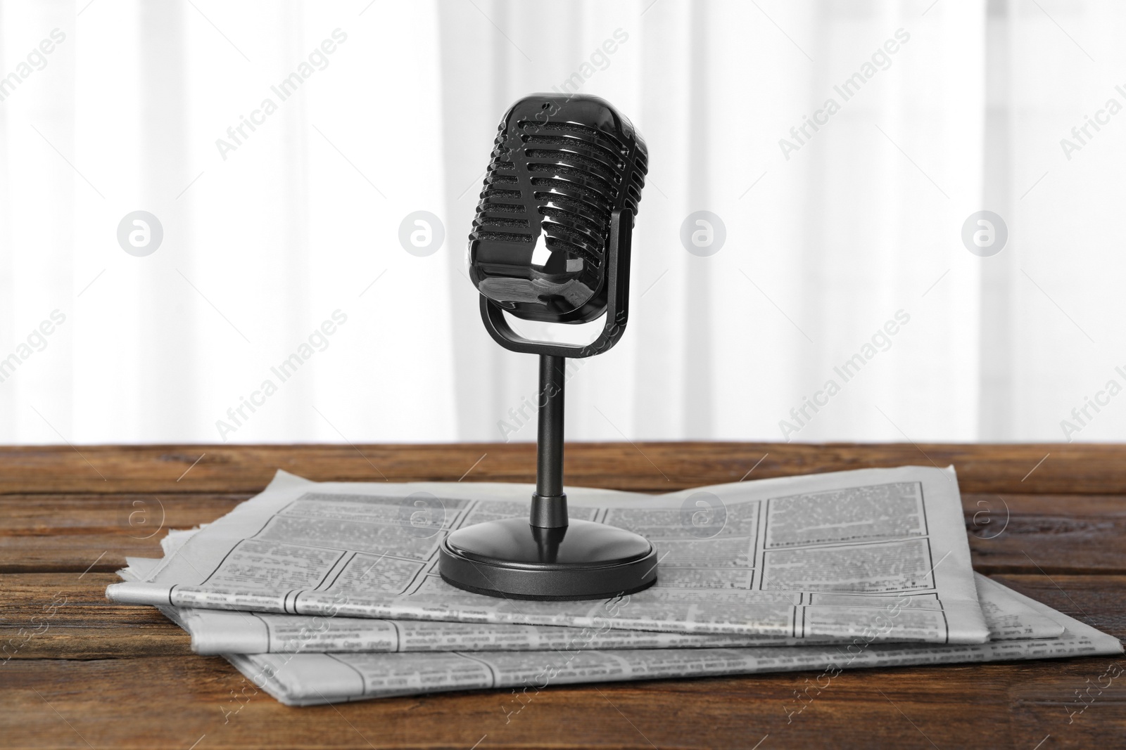 Photo of Newspapers and vintage microphone on wooden table. Journalist's work