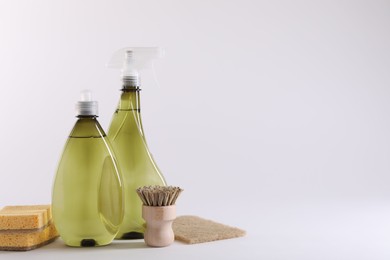 Bottles of cleaning product, brush and sponges on white background