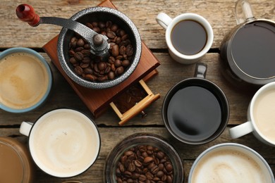 Photo of Different coffee drinks in cups, beans and manual grinder on wooden table, flat lay