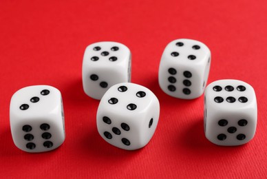 Photo of Many white game dices on red background, closeup