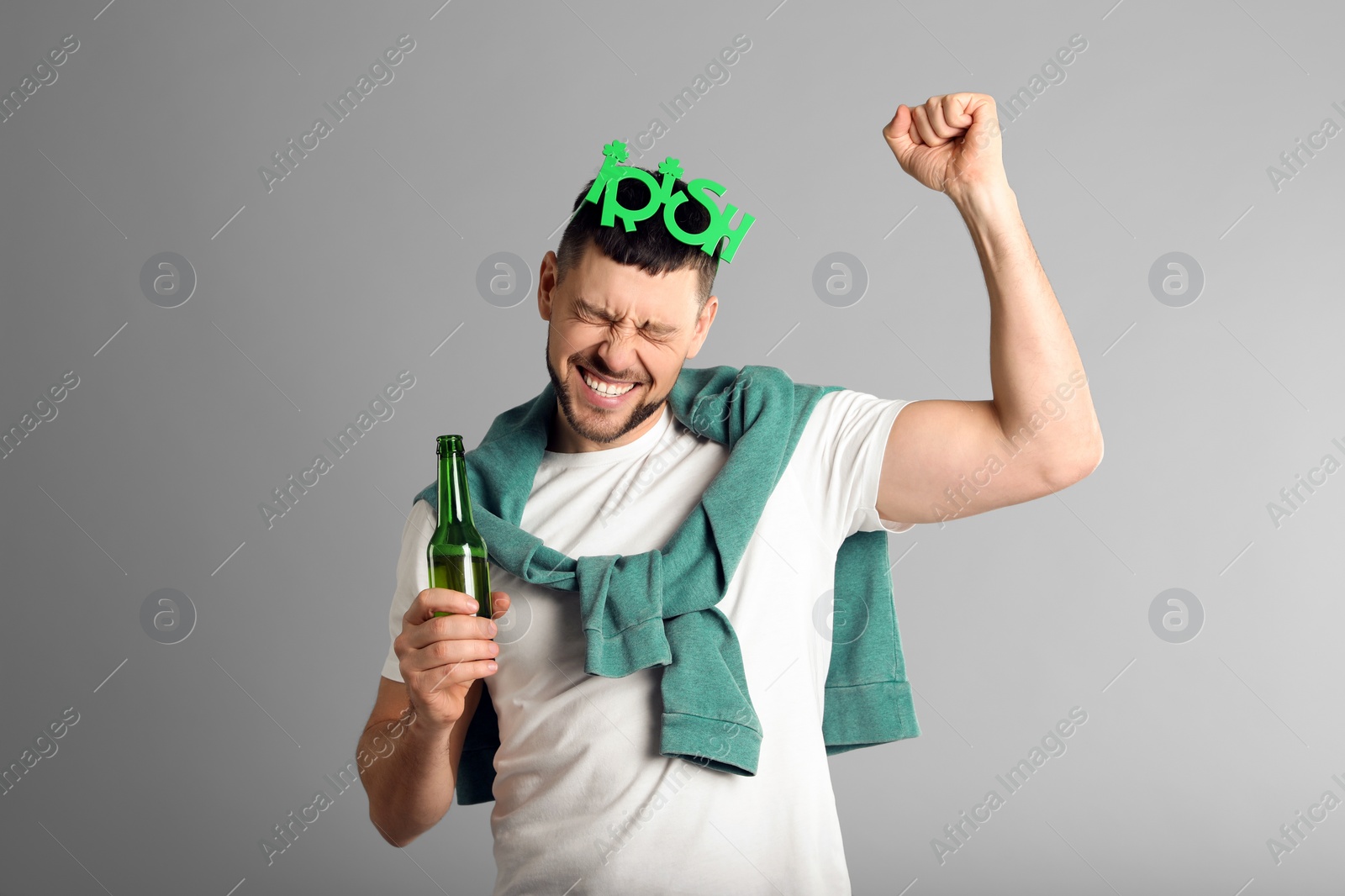 Photo of Emotional man in St Patrick's Day outfit with beer on light grey background