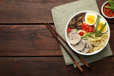 Photo of Delicious ramen with meat in bowl served on wooden table, flat lay. Space for text. Noodle soup