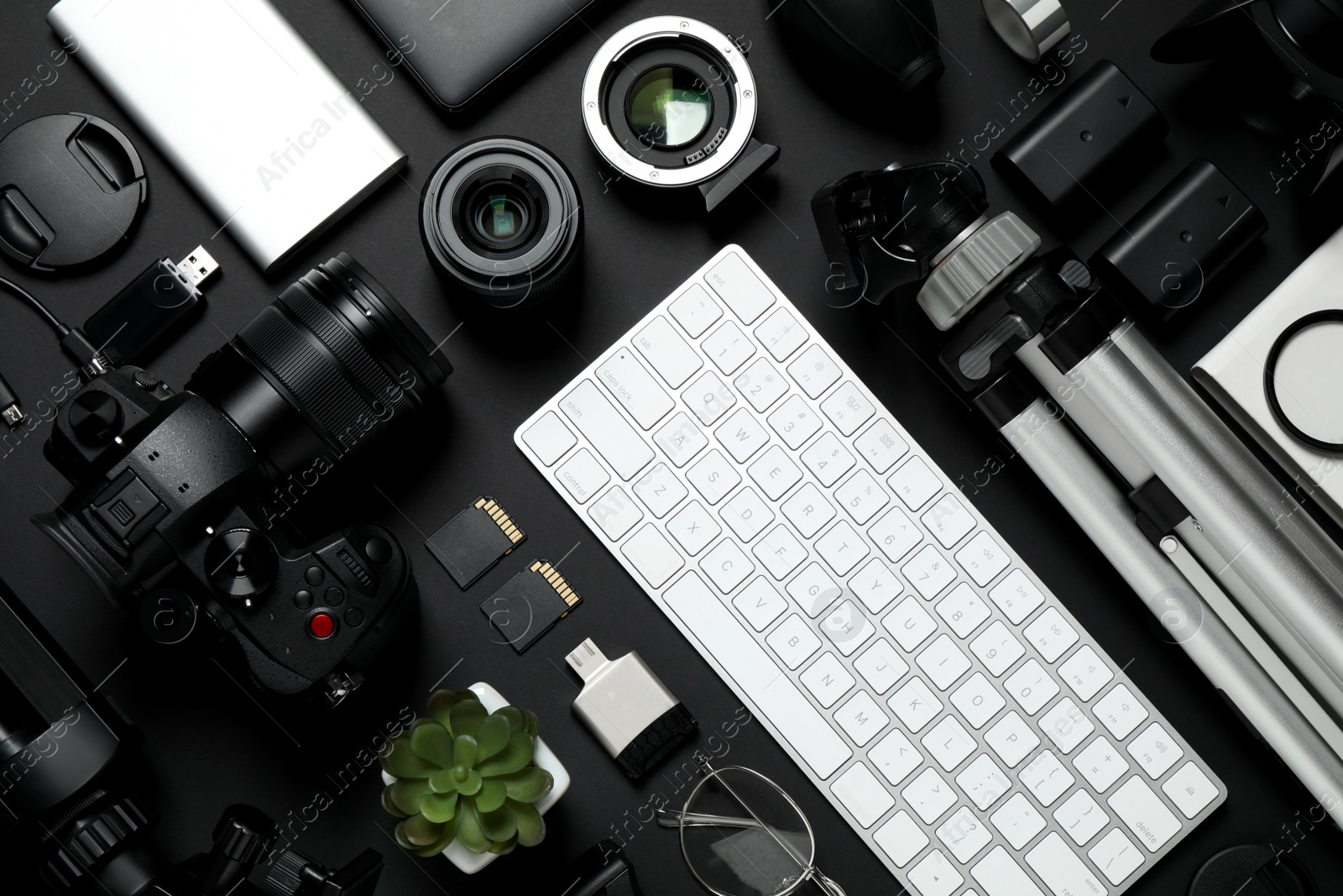 Photo of Flat lay composition with camera, video production equipment and computer keyboard on black background