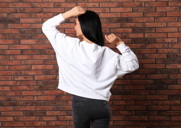 Young woman in sweater at brick wall. Mock up for design