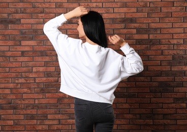 Photo of Young woman in sweater at brick wall. Mock up for design