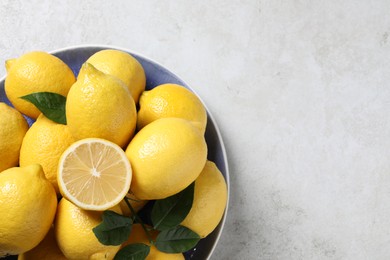 Fresh lemons and green leaves on light table, top view. Space for text