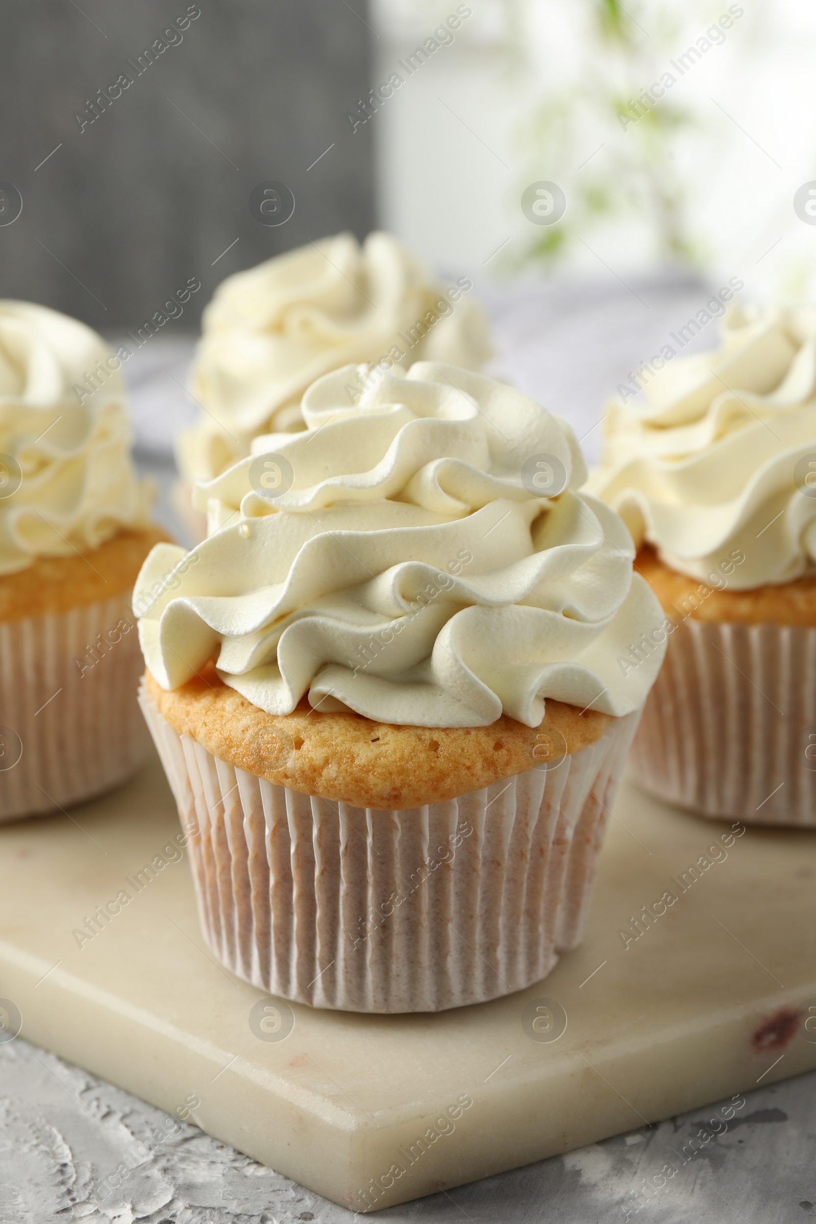 Photo of Tasty cupcakes with vanilla cream on grey table, closeup