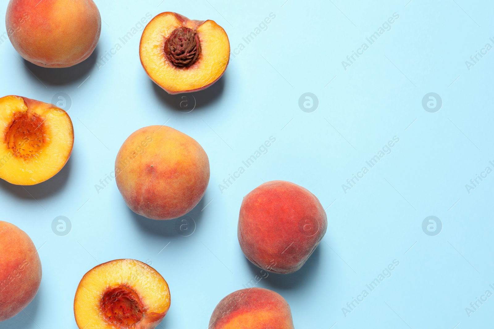 Photo of Cut and whole fresh ripe peaches on light blue background, flat lay. Space for text