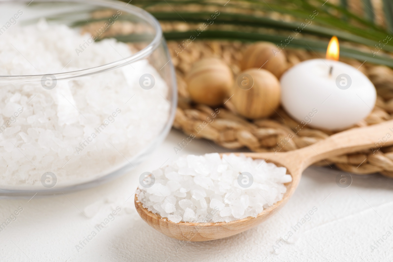 Photo of Wooden spoon with sea salt for spa scrubbing procedure on white table, closeup