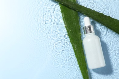 Bottle of cosmetic product and aloe leaves in water on light blue background, flat lay. Space for text