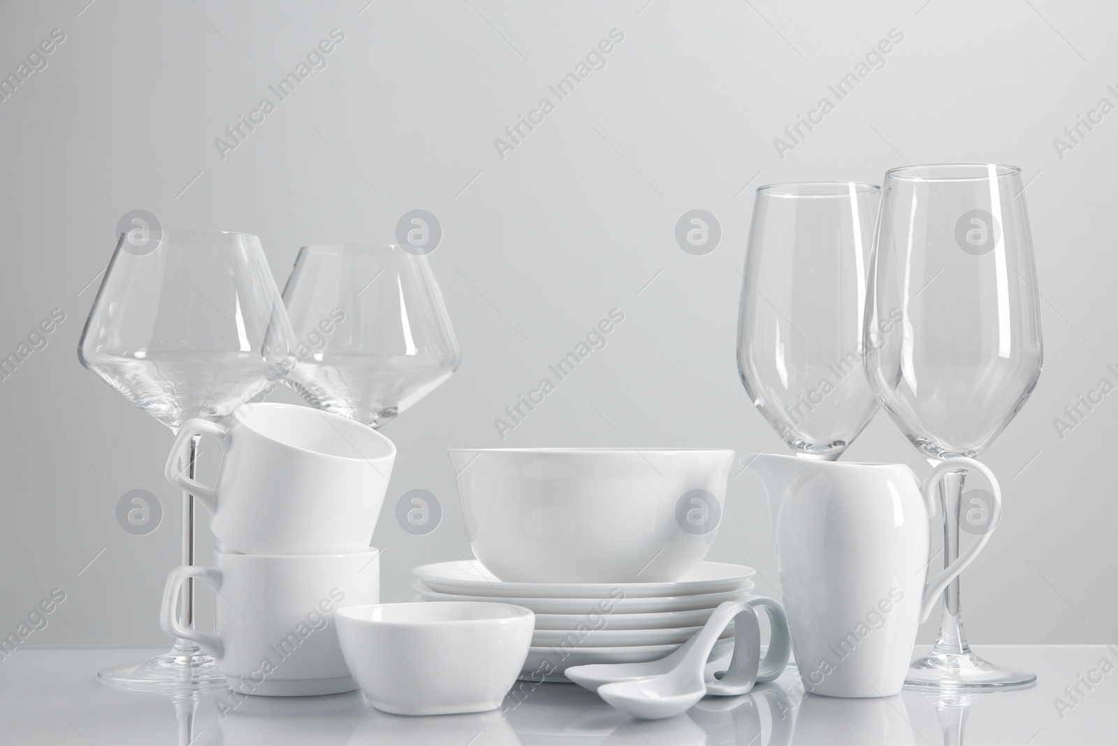 Photo of Set of many clean dishware and glasses on light table