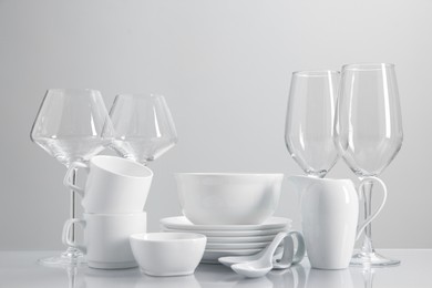 Set of many clean dishware and glasses on light table