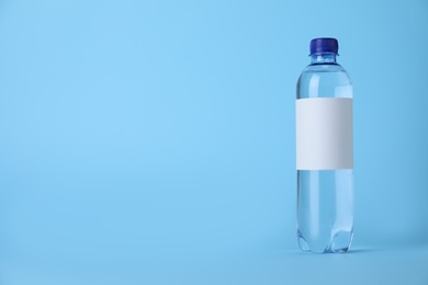 Plastic bottle with soda water on light blue background. Space for text