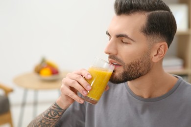Photo of Handsome man drinking delicious smoothie at home. Space for text