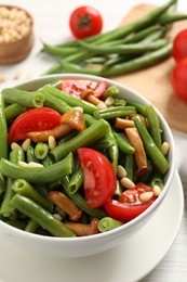 Photo of Delicious salad with green beans, mushrooms, pine nuts and tomatoes on table, closeup