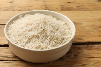 Photo of Raw basmati rice in bowl on wooden table