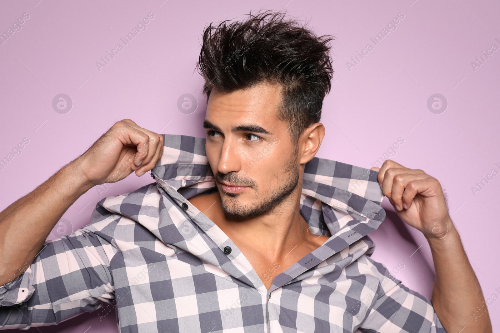 Photo of Young man with trendy hairstyle posing on color background