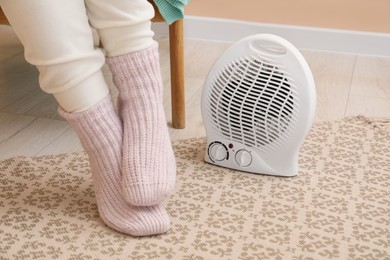 Woman near modern electric fan heater indoors, closeup