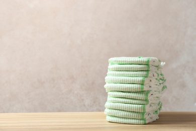 Photo of Stack of diapers on table against color background, space for text. Baby accessories