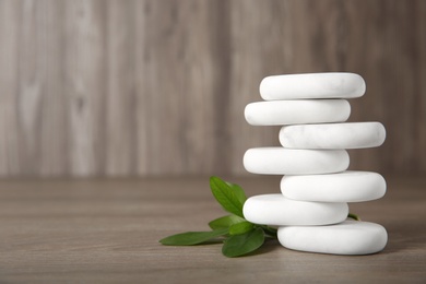 Photo of Stack of marble spa stones with branch on wooden background. Space for text