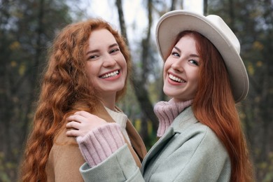 Photo of Portrait of beautiful young redhead sisters in park on autumn day