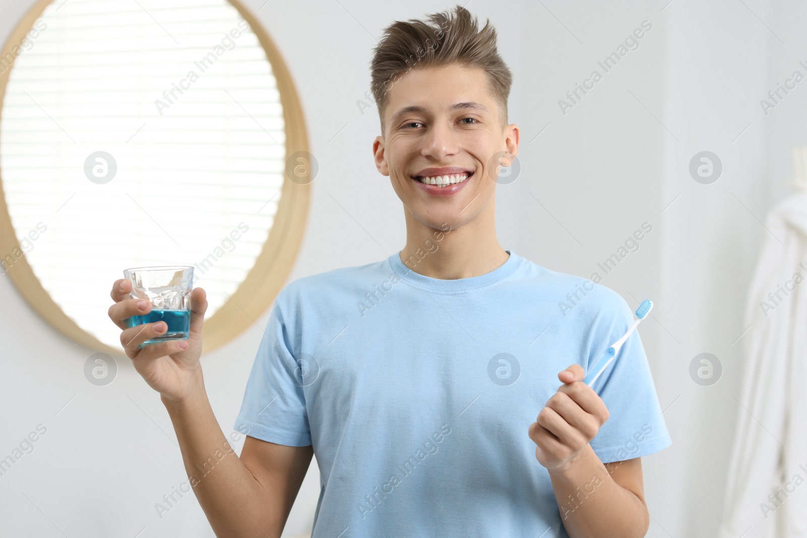 Photo of Young man with mouthwash and toothbrush in bathroom