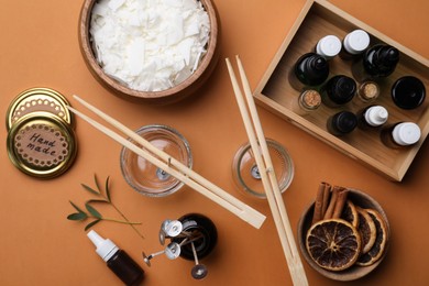 Flat lay composition with ingredients for homemade candles on brown background