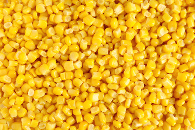 Photo of Delicious canned corn kernels as background, top view