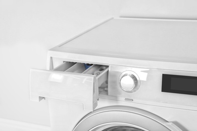 Washing machine with open detergent drawer on white background, closeup. Laundry day