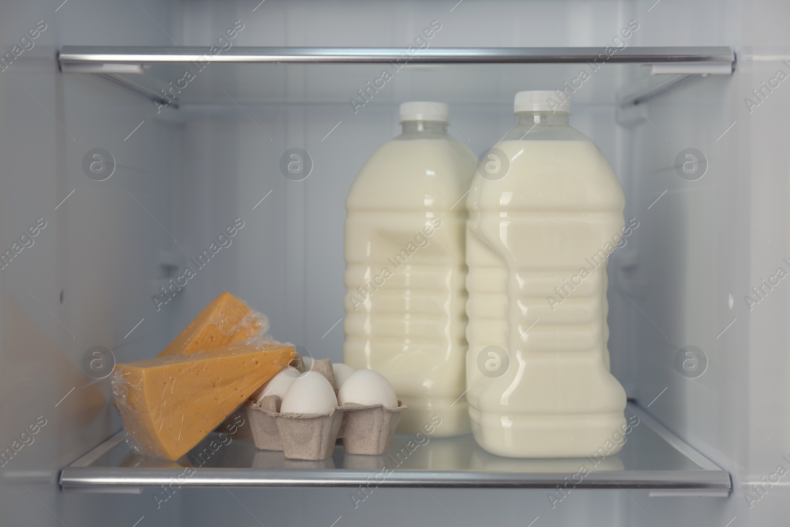 Photo of Gallons of milk, eggs and cheese in refrigerator, closeup